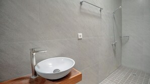 Une salle de bain avec un lavabo blanc, une douche et des murs carrelés.