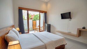 Une chambre d’hôtel équipée d’un lit, d’un bureau, d’une chaise, d’un téléviseur fixé au mur et d’une porte-fenêtre coulissante donnant sur un espace extérieur.