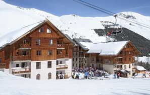 Eine Holzhütte mit mehreren Balkonen, einer Skiliftanlage und einer Menschenmenge.