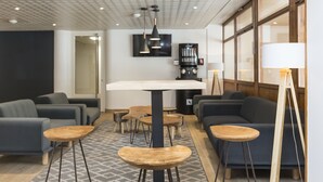 A modern lounge area with sofas, tables, and a TV mounted on the wall. - Résidence Odalys L'orée des Pistes (Saint-Sorlin-d'Arves)
