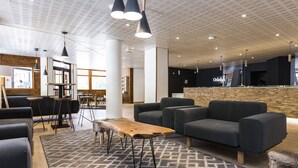 A modern lounge area with sofas, a coffee table, pendant lighting, and a reception desk. - Résidence Odalys L'orée des Pistes (Saint-Sorlin-d'Arves)