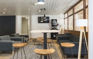 A modern lounge area with sofas, tables, and a TV mounted on the wall.