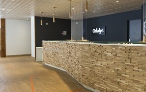 A reception desk with a modern design, a sign reading 'Odaly's,' and a wooden wall feature.