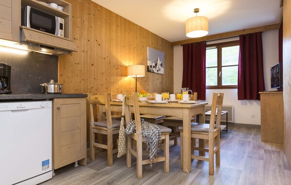Une pièce aux murs lambrés, comprenant une table à manger, des chaises, un four à micro-ondes, une machine à café et une lampe.
