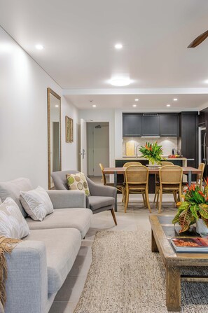 A modern living room with a sofa, chairs, a coffee table, and a dining area with a table and chairs.