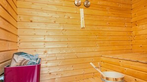 Una sauna de madera con un banco, un cubo y un termómetro en la pared.