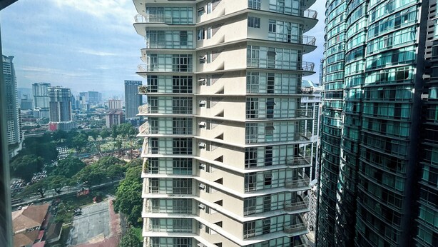 A multi-story building with balconies and large windows, surrounded by other high-rise buildings.