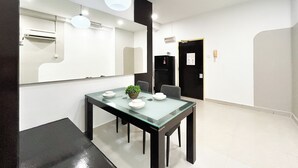 A modern dining area with a glass table, chairs, and a potted plant.