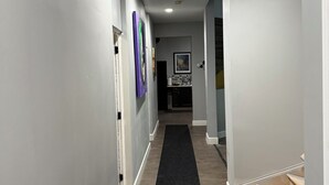 A hallway with a black carpet, white walls, and a wooden staircase. - Spacious 2BR Full Kitchen Suite + Pool Table I
Patio + Private (Lawrenceville)