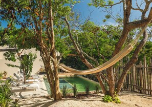 A hammock between trees, a pool, and a building with outdoor seating. - Luxury vacation villa with pool in Isla Mujeres Mexico (Isla Mujeres)