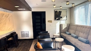 Un salon moderne avec un canapé, des fauteuils en cuir noir et une table basse.