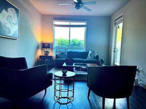 Ein Wohnzimmer mit einer Couch, zwei Sesseln, einem Couchtisch und einem Deckenventilator.