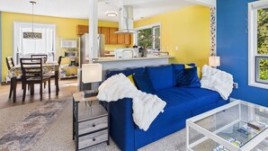 A compact living space with a blue sofa, a small coffee table, and a dining area with a table and chairs.