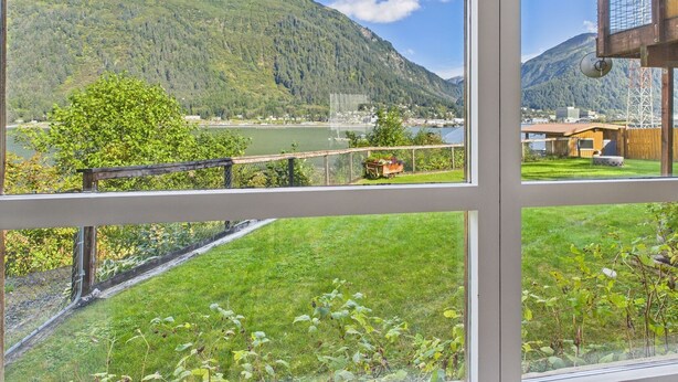 A view from a window overlooking a lake, mountains, and a small town.