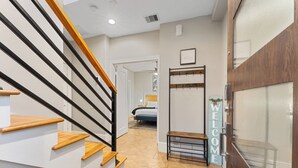 A modern interior with a wooden staircase, a welcome sign, and a bed in the background. - EaDo Escape • Sleeps 10 - Private Yard & Driveway + Rooftop City Views (Houston)
