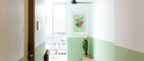 A hallway with a fire extinguisher, a bench, and a wall-mounted artwork.