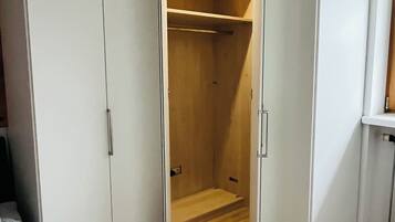 A walk-in closet with white doors and a wooden interior.