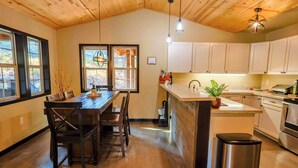 Una cocina con armarios de madera, una isla central y un comedor con mesa y sillas de madera.