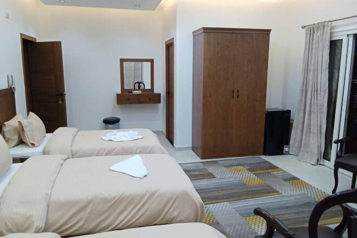 Habitació d'hotel amb dos llits, un armari, un mirall i una taula petita.