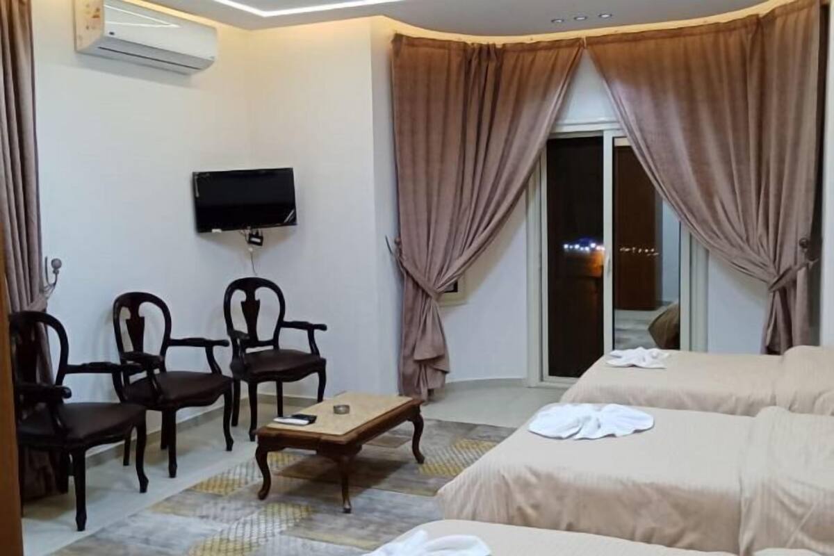 Habitació d'hotel amb televisió, dues cadires de fusta, una taula petita, dos llits i una porta corredissa de vidre.