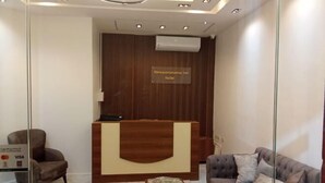 A reception area with a wooden reception desk, a sofa, a chair, and a small table. - New Panorama Inn (Cairo)