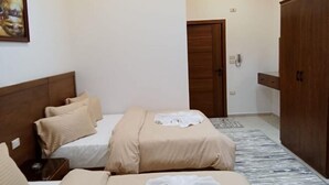 A hotel room with two beds, a wooden wardrobe, a painting on the wall, and a ceiling light. - New Panorama Inn (Cairo)