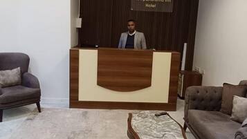 A reception desk with a sign reading 'Newpanorama Inn Hotel' in a hotel lobby with two sofas and a coffee table.