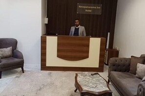 A reception desk with a sign reading 'Newpanorama Inn Hotel' in a hotel lobby with two sofas and a coffee table. - New Panorama Inn (Cairo)