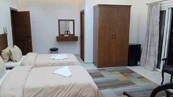 A hotel room with two beds, a wardrobe, a mirror, and a small table.