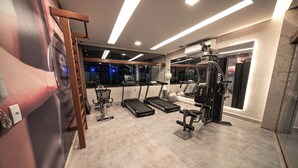 A modern gym with treadmills, a weight bench, and dumbbells. - Cozy home with Wi-Fi, air conditioning and great location in Muro Alto/PE (Ipojuca)