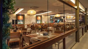 A modern restaurant with wooden tables, chairs, and hanging rattan lamps. - Cozy home with Wi-Fi, air conditioning and great location in Muro Alto/PE (Ipojuca)