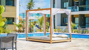 A poolside area with a wooden canopy bed, lounge chairs, and a swimming pool. - Cozy home with Wi-Fi, air conditioning and great location in Muro Alto/PE (Ipojuca)