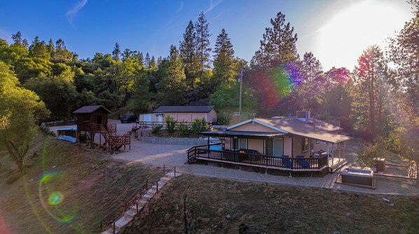 A cabin with a deck, a covered porch, and a small building with a garage.