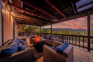 A covered outdoor seating area with wicker furniture and a fire feature. - 9 Acre Mountain Escape with Hot Tub, Game Room, Fire Pit, BBQ (North Fork)
