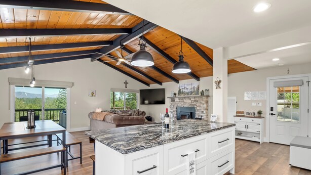 A spacious kitchen with a large island, wooden beams, and a stone fireplace.