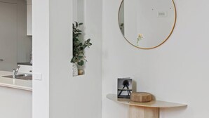 Un bagno moderno con un lavandino bianco, uno specchio con cornice dorata e un piccolo tavolino in legno con un libro e un oggetto decorativo.