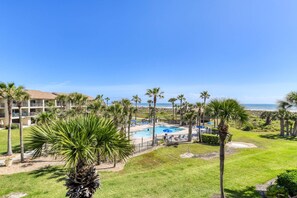 Un complexe hôtelier doté d’une piscine, de palmiers et offrant une vue sur l’océan.