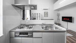 A modern kitchen with a stainless steel range, a built-in oven, and a sink. There is a flat-screen TV mounted on the wall displaying "NETFLIX". - FURANO RESORT WAKABA D (Furano)