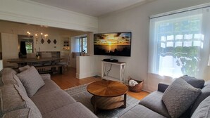A modern living room with a large sofa set, a wooden coffee table, and a flat-screen TV mounted on the wall. - Rosewood Landing- Hot tub & Sauna- Sleeps 10 (Medford)