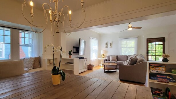 A spacious living room with a wooden floor, a sofa, a coffee table, and a TV. - Rosewood Landing- Hot tub & Sauna- Sleeps 10 (Medford)