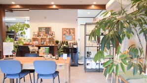 A restaurant with a wooden counter, blue chairs, and a large plant. - Izu-Kogen Tent Resort (Ito)