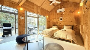 A wooden cabin with two beds, a dining table, and a grill outside. - Izu-Kogen Tent Resort (Ito)