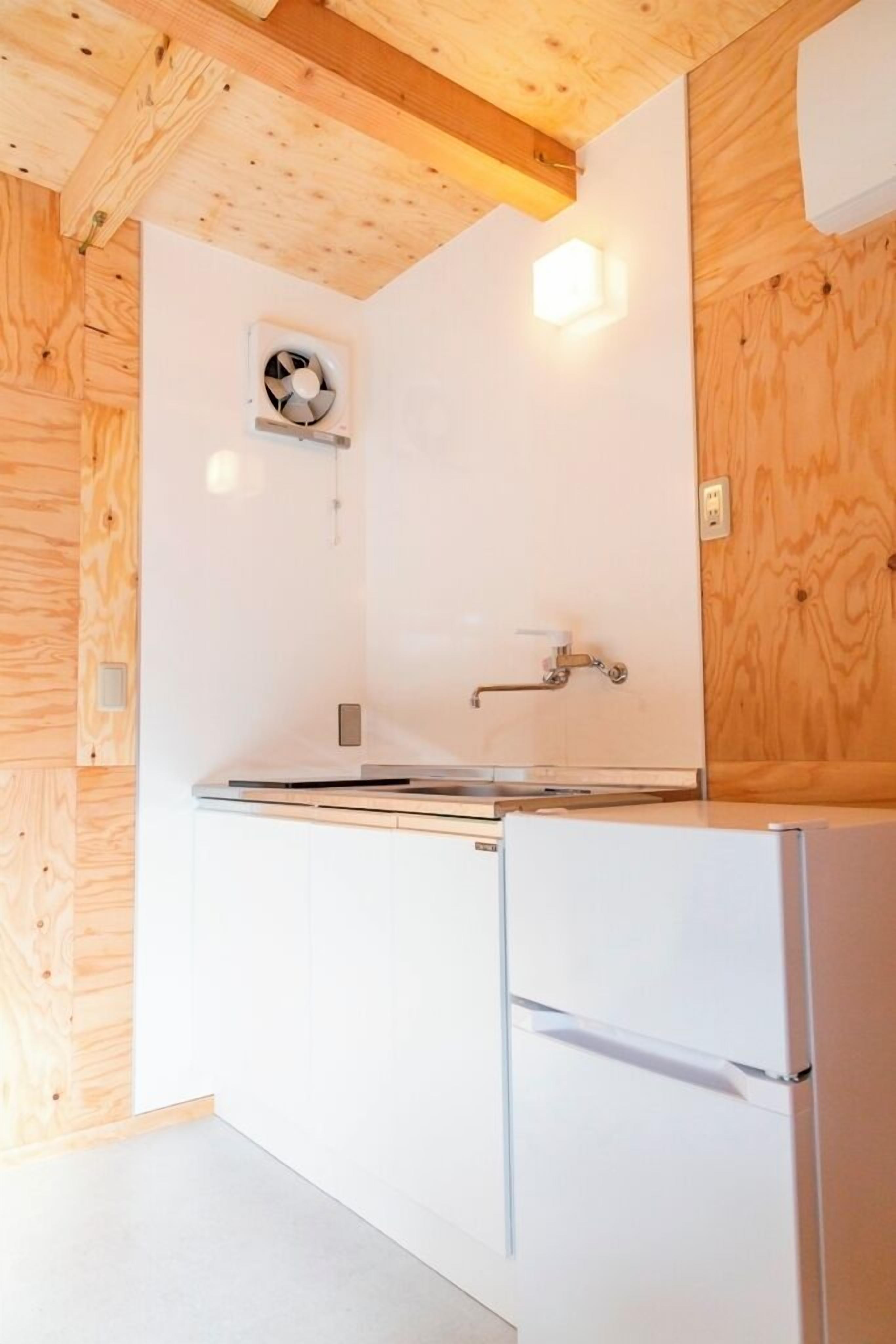 A kitchen with white cabinets, a stainless steel countertop, a built-in oven, and a wall-mounted fan.