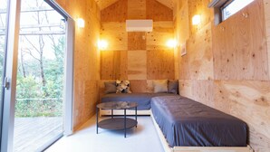 A compact wooden cabin with a bed, a small table, and a window. - Izu-Kogen Tent Resort (Ito)