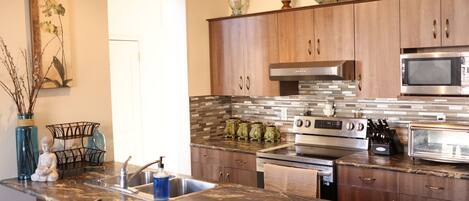 A kitchen with wooden cabinets, a stainless steel microwave, and a granite countertop.