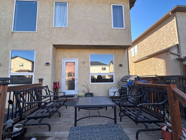 A patio with a table and chairs, a grill, and a door with a glass panel.
