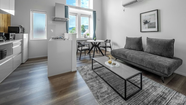 Un apartamento moderno con cocina, comedor y sala de estar. Cuenta con un sofá, una mesa de centro y una mesa de comedor con sillas.