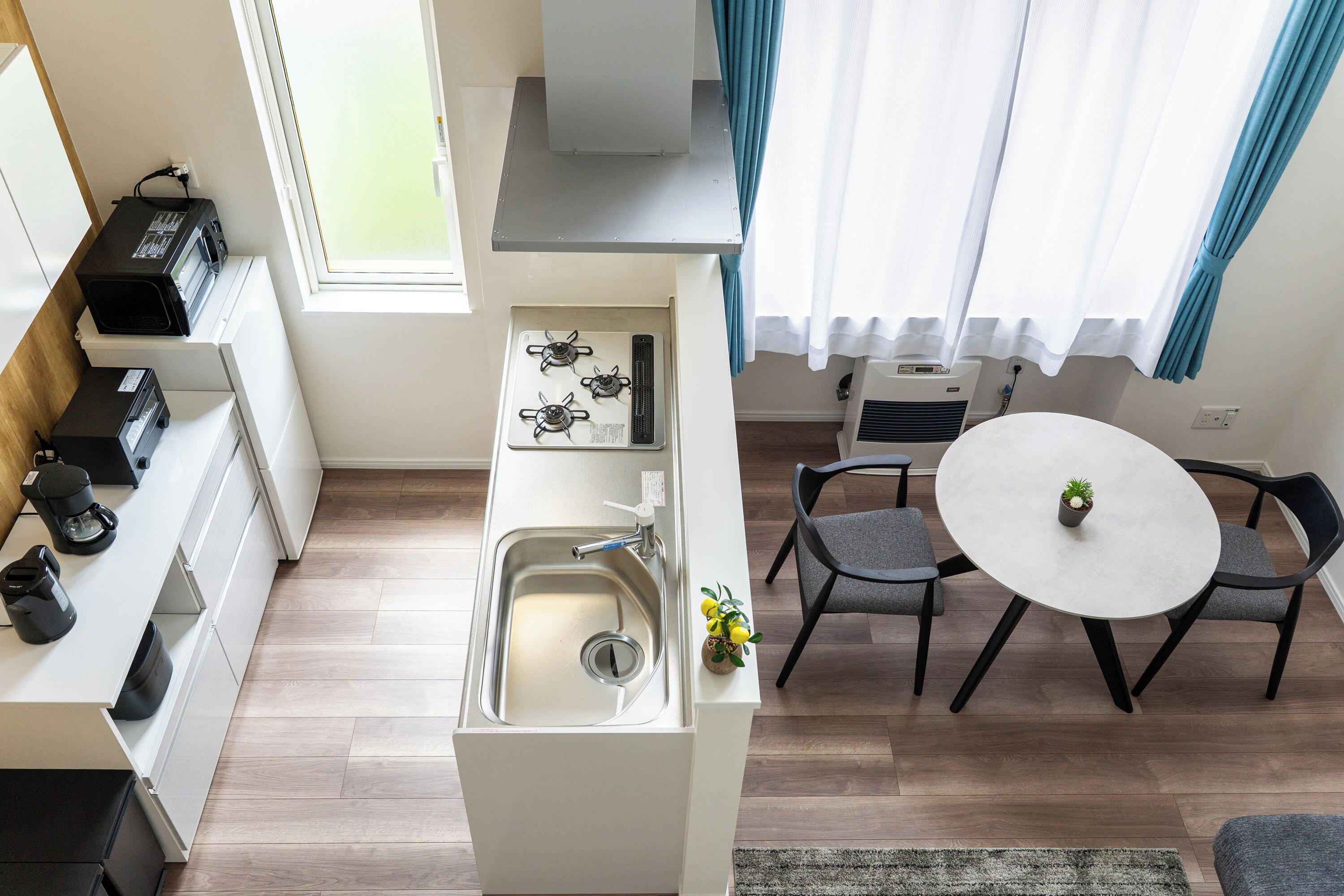 A compact kitchen with a sink, stove, and a dining area with a table and chairs.
