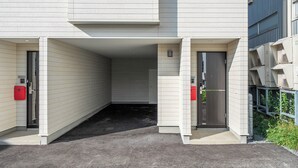 Un edificio con un acceso cubierto, un buzón rojo y una puerta.