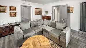 Un salon avec un canapé d’angle gris, une table basse en bois et un tapis à motifs.